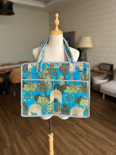 Tote bag with a blue and green tropical shell and palm tree pattern.