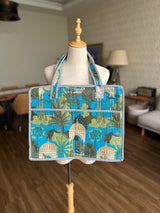 Tote bag with a blue and green tropical shell and palm tree pattern.